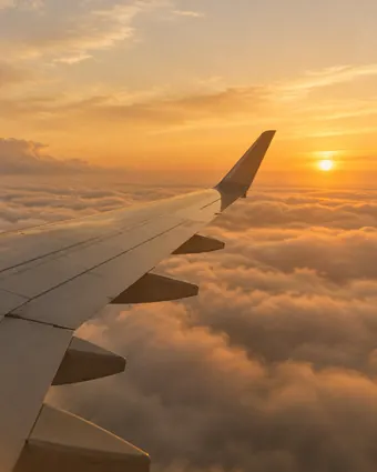 An aircraft wing above a golden layer of cloud