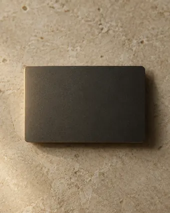 A plain metal credit card on cream stone