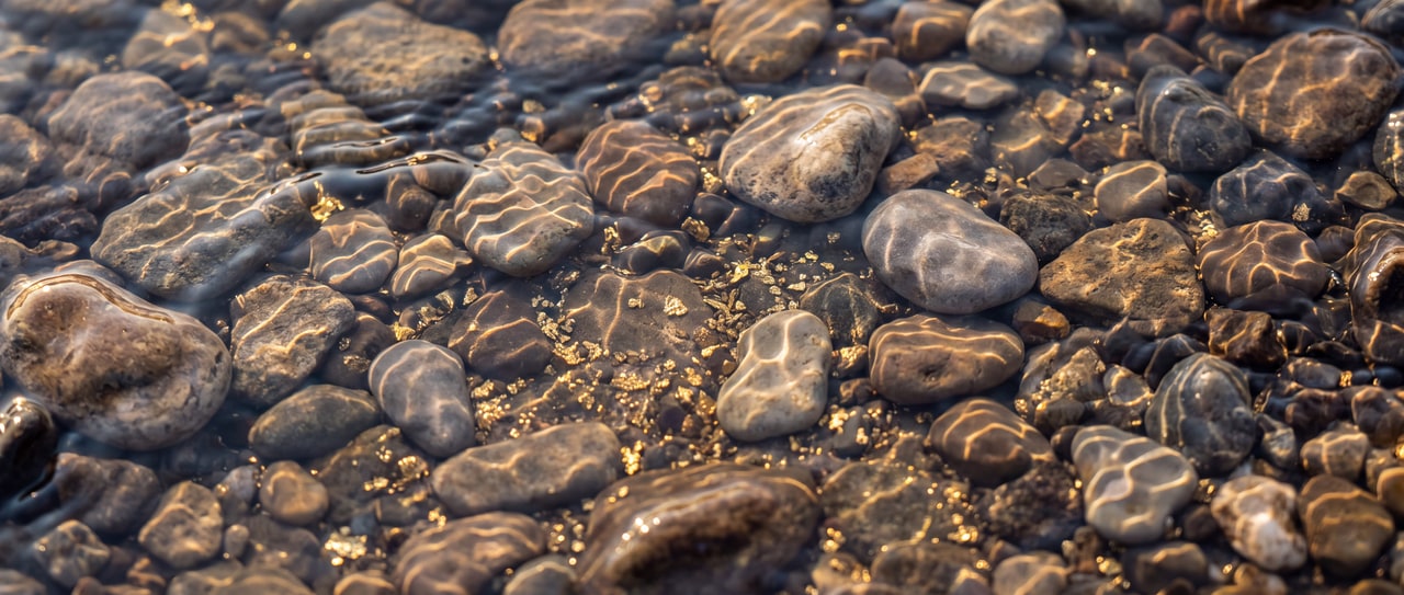 A river bed of pale stones under moving water.